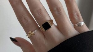 Hand med guldringar, silverring och hängsmycke i blandade metaller